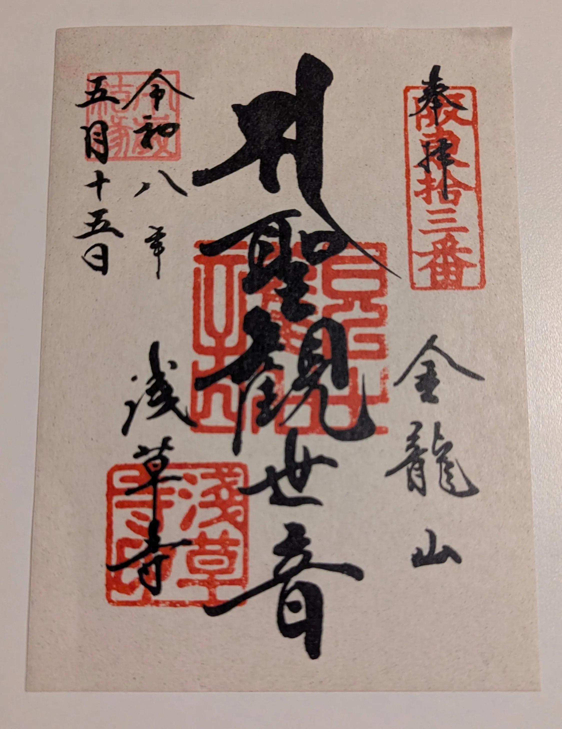 Loose sheet of paper with a goshuin: Japanese writing in four red stamps with black writing overlaid