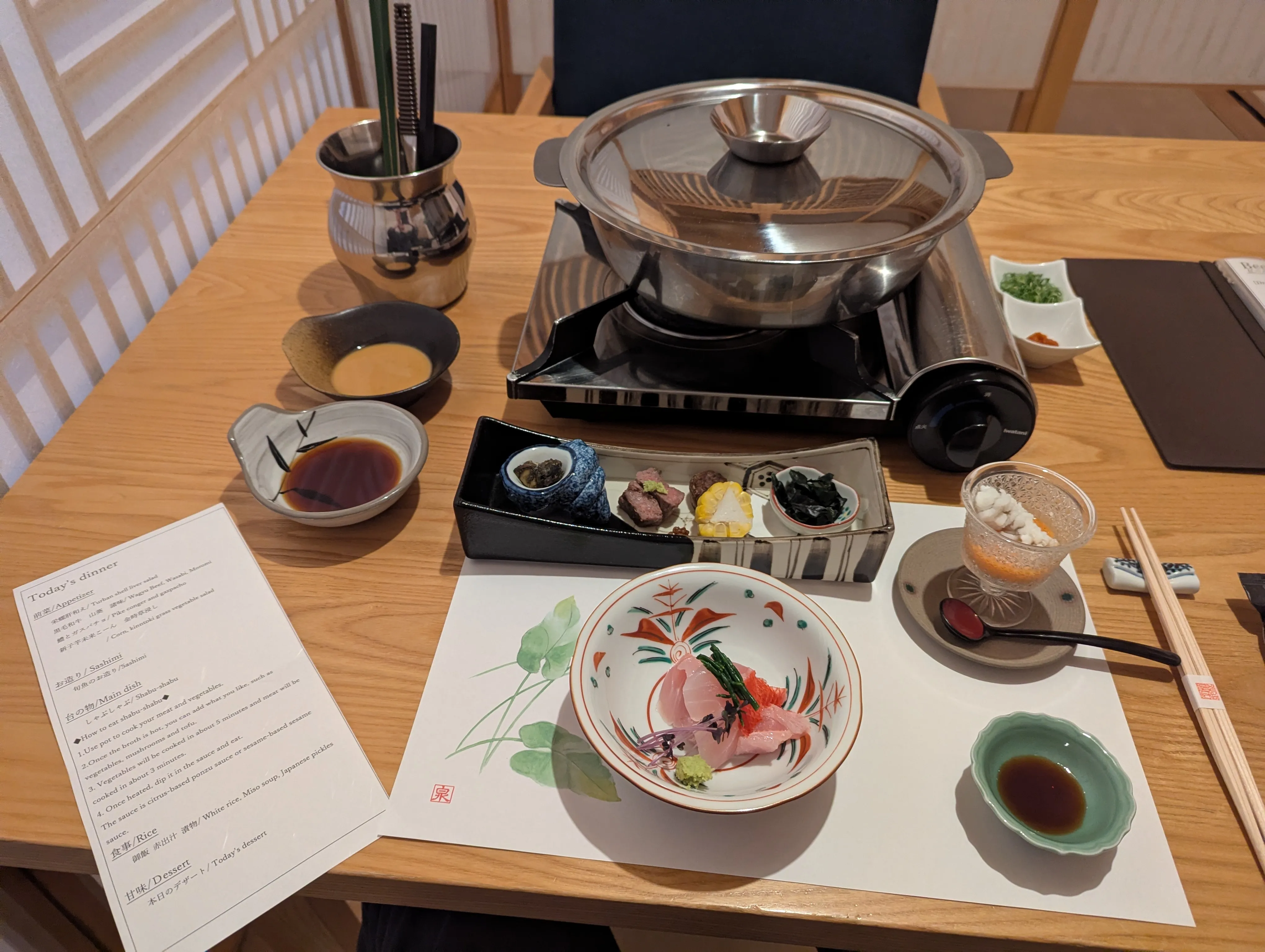 Japanese appetizers including sashimi in front of a hot pot