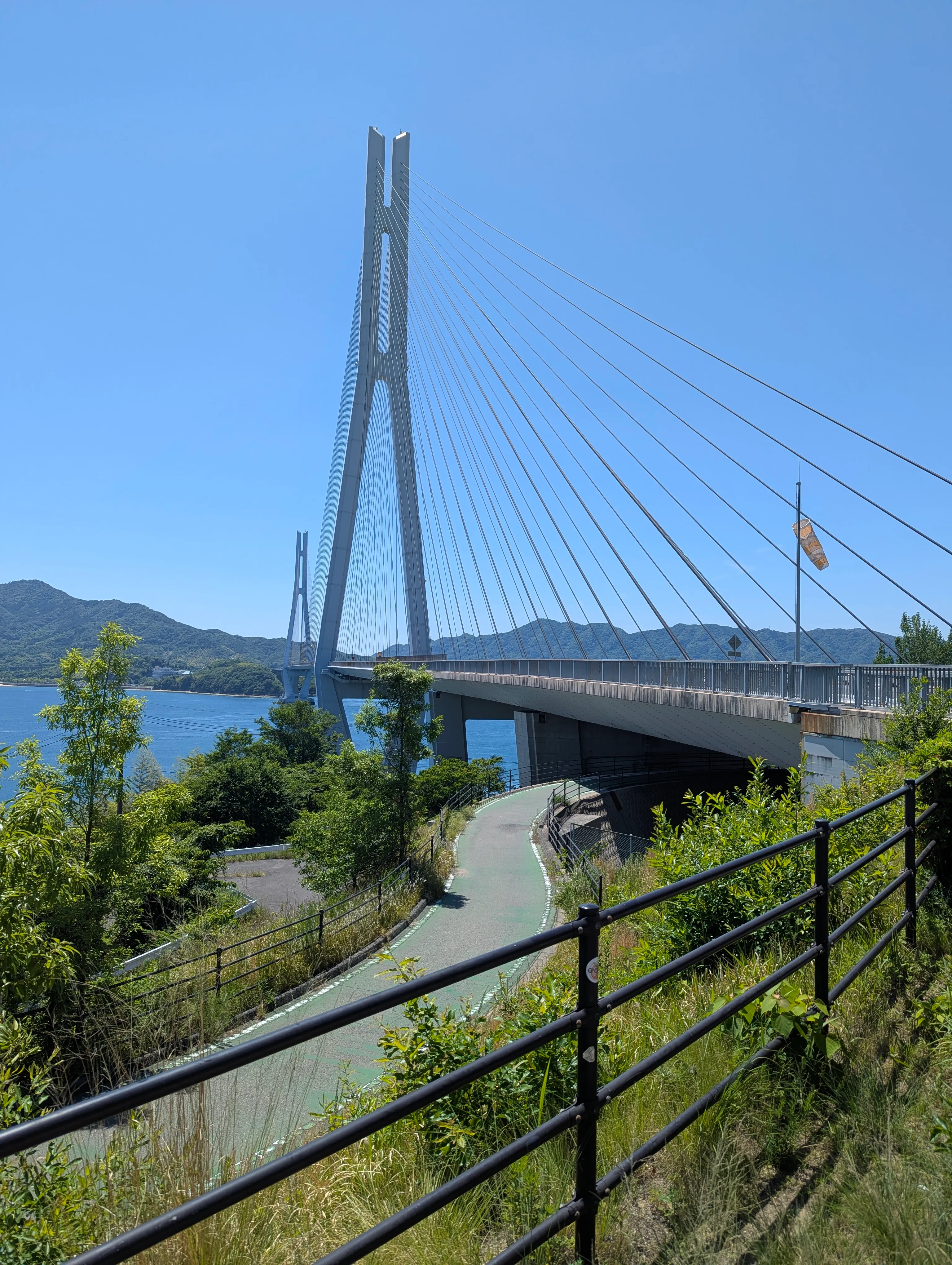 Winding bike path leads up to a suspension bridge to a distant island